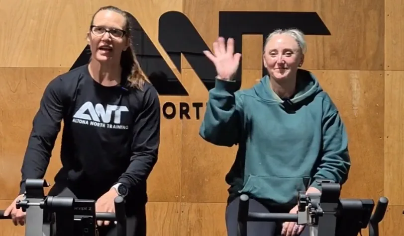 Two ANT coaches waving from the ski ergs