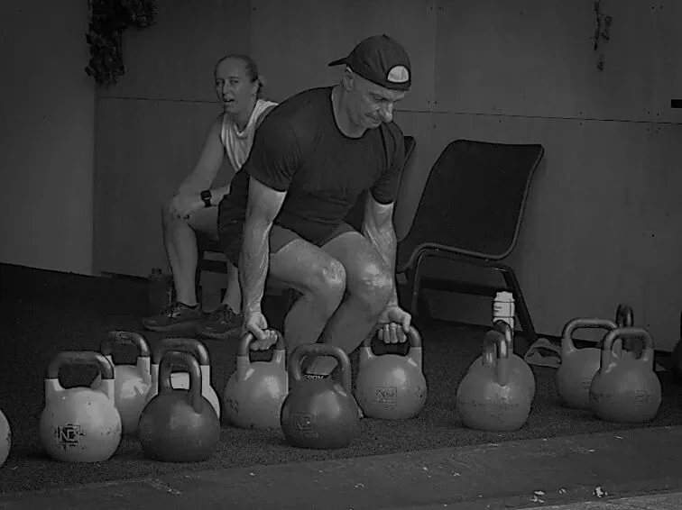 Coach demonstrating kettlebell technique to a member
