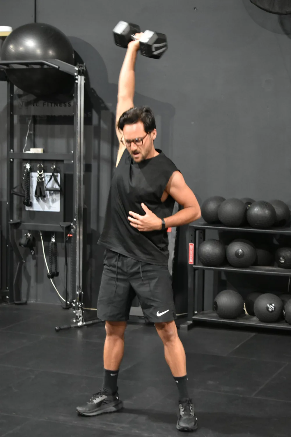 Member pressing a dumbbell overhead in the early morning session