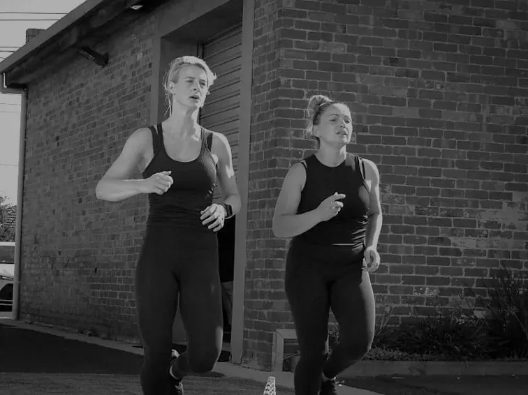 Two members running outside the gym during a conditioning session